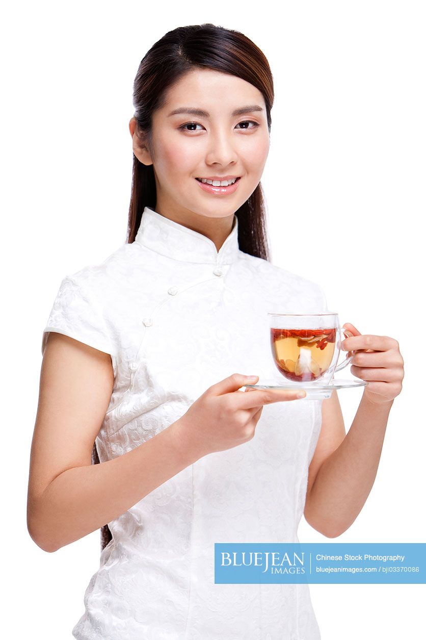 Young beautiful Chinese woman in traditional cheongsam with herbal tea