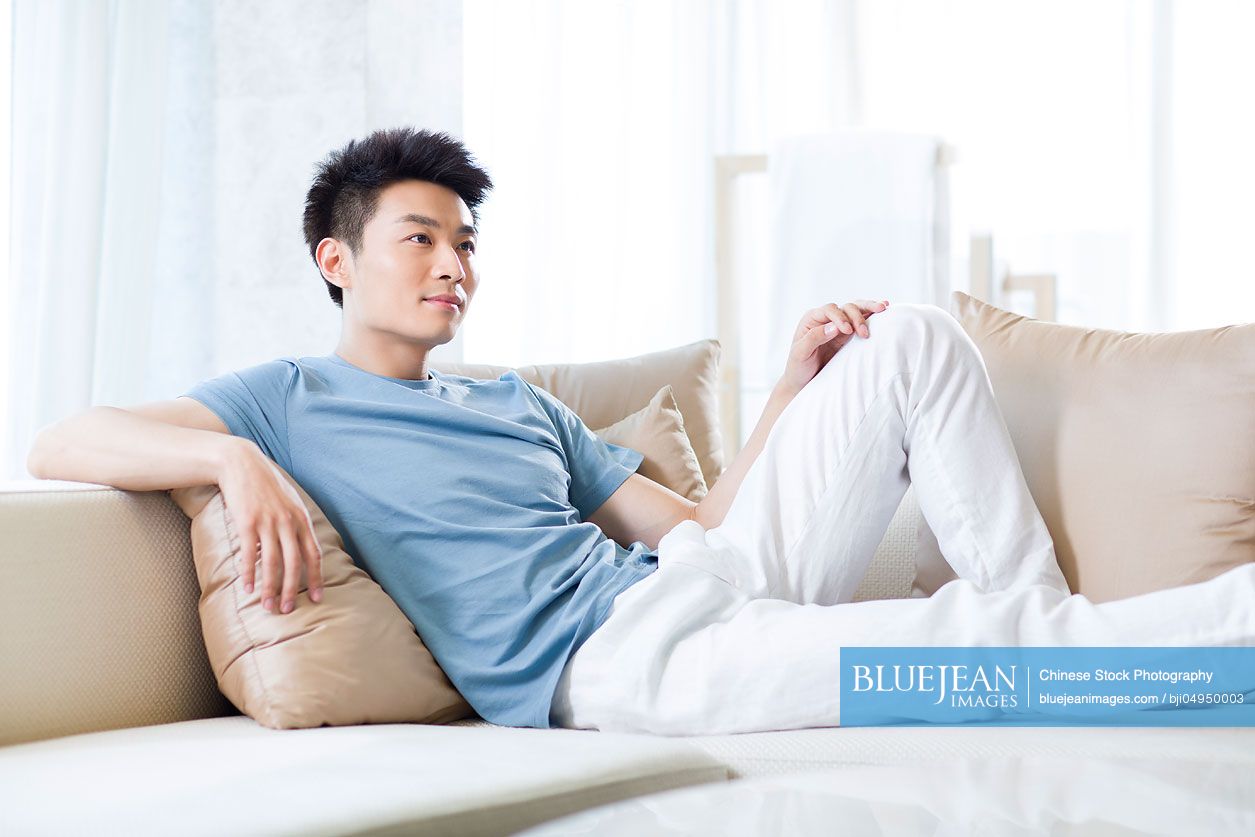 Young Chinese man relaxing on the sofa