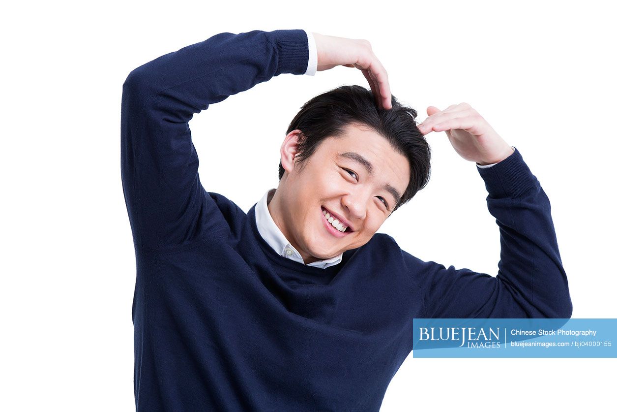 Cheerful young Chinese man doing heart shape gesture