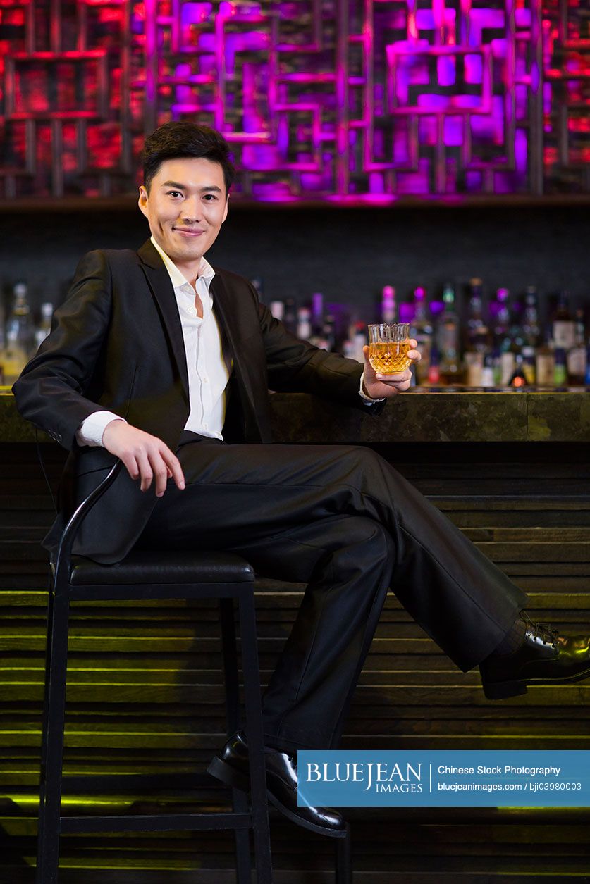 Young Chinese man having a drink at bar