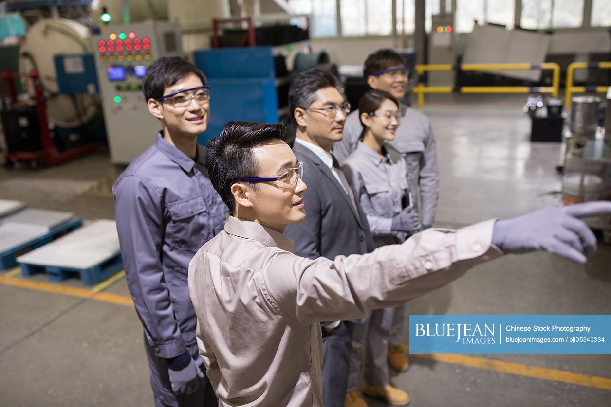 Confident Chinese businessman and engineering team in the factory