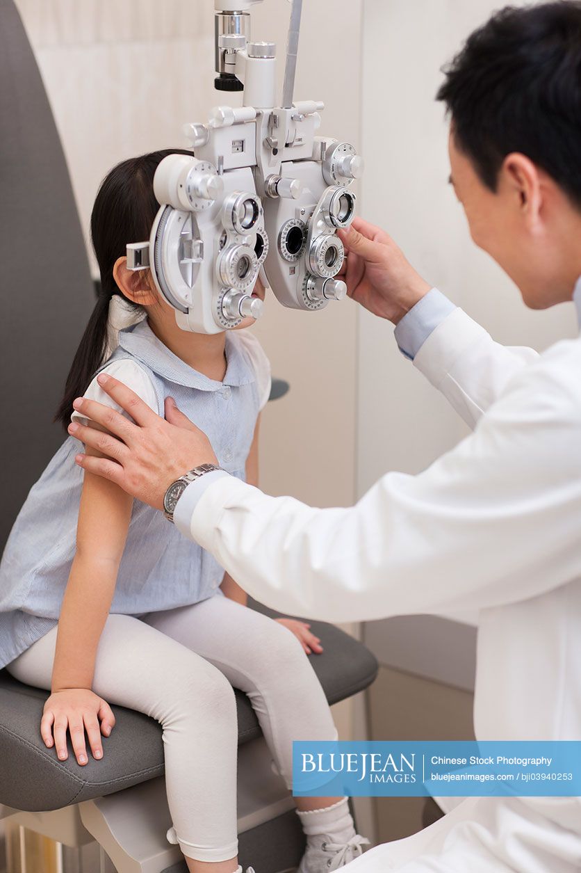 Chinese doctor examining girl's eyes