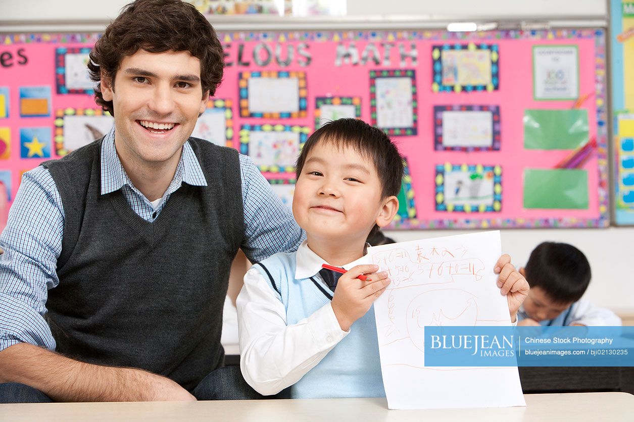 Teacher sitting with a Chinese student who is displaying his work