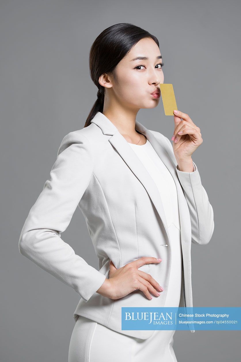 Happy young Chinese businesswoman holding a credit card