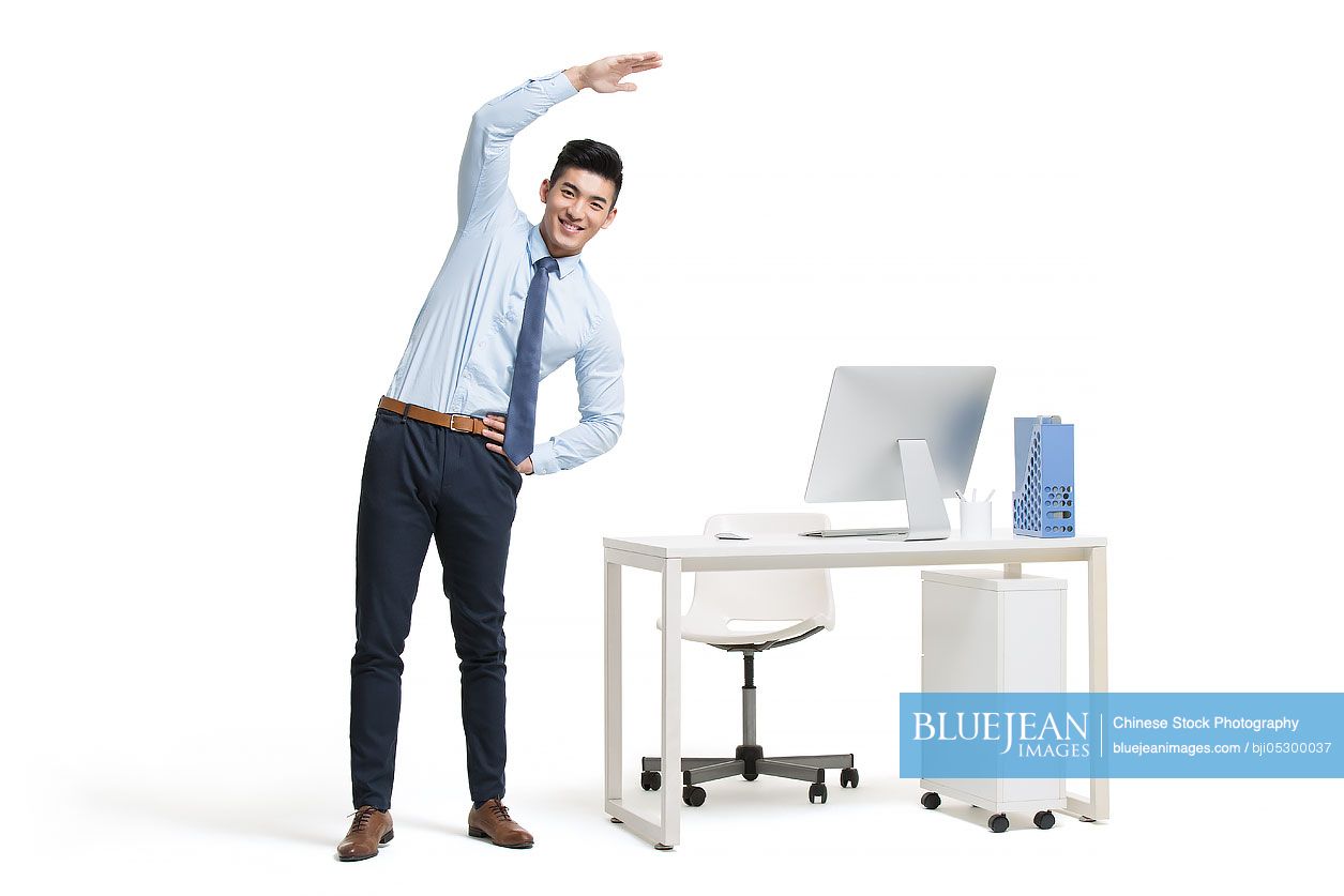 Young Chinese businessman exercising in office