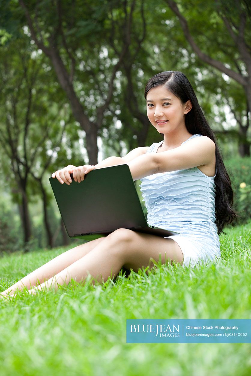 Young Chinese woman sitting on meadow