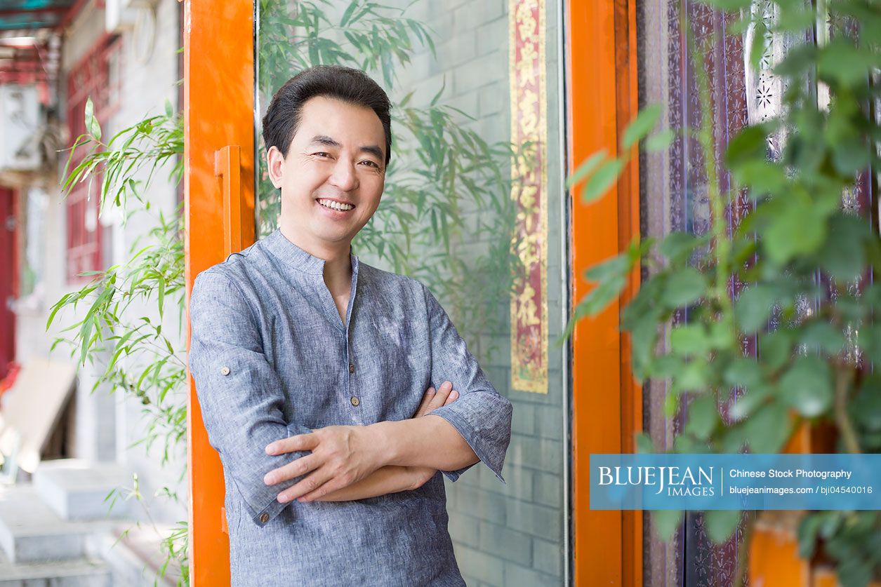 Chinese male shopkeeper standing in doorway of his store