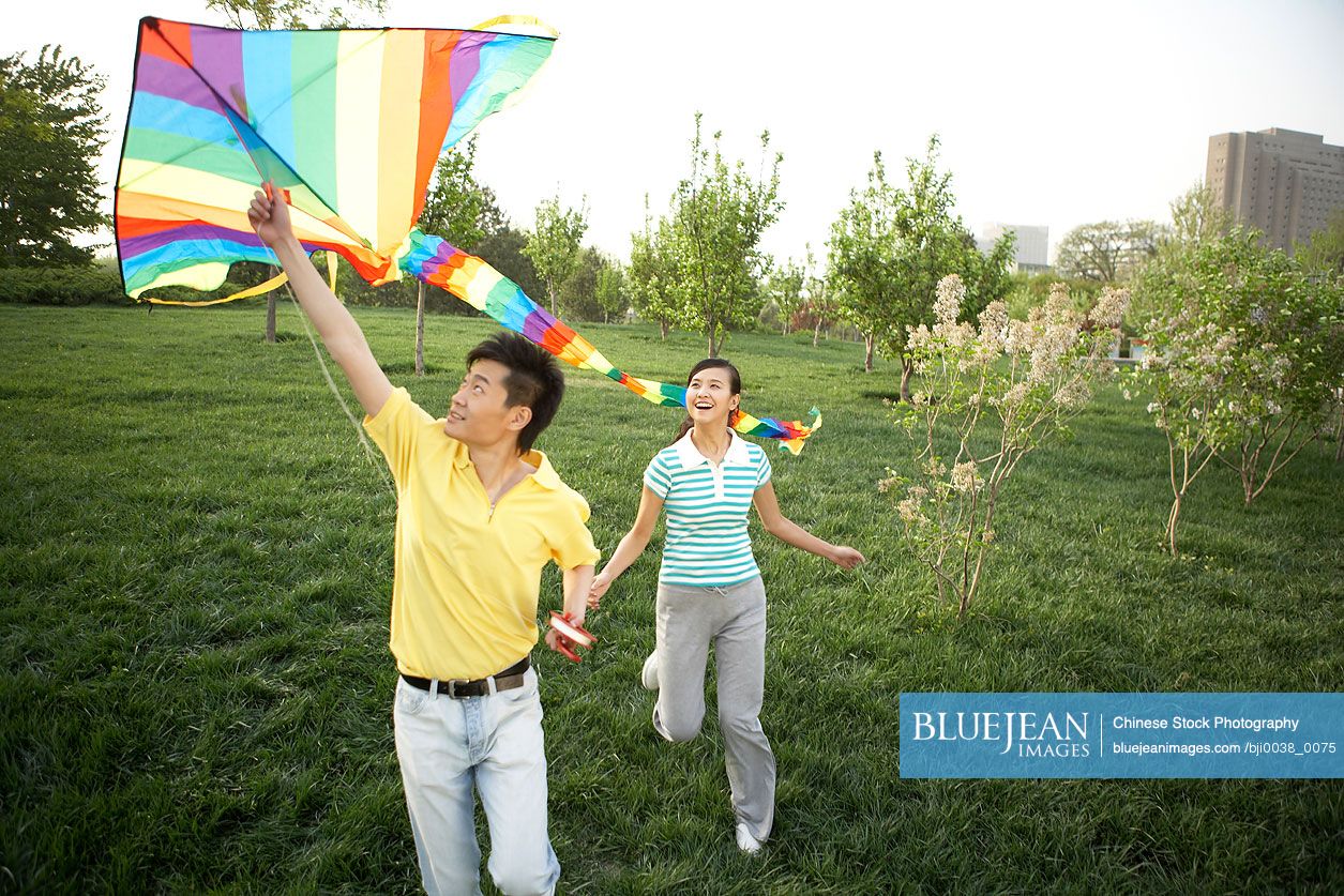 Young Chinese couple flying kite in park