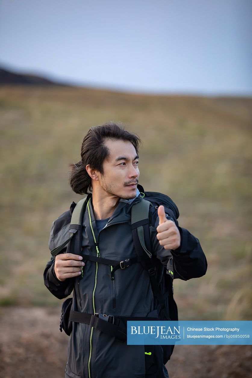 Chinese mid adult man hitchhiking on the road