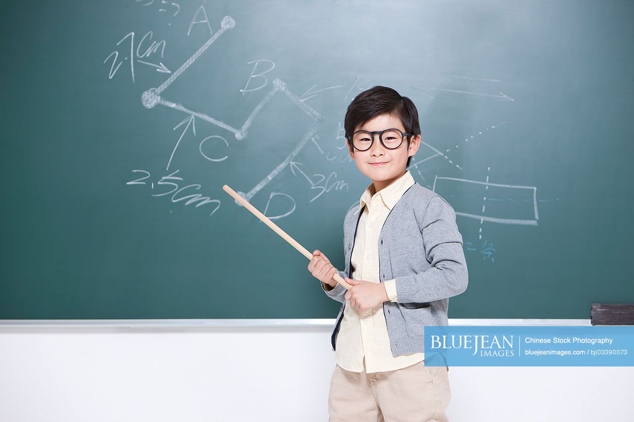 Active little Chinese boy playing Chinese teacher in classroom