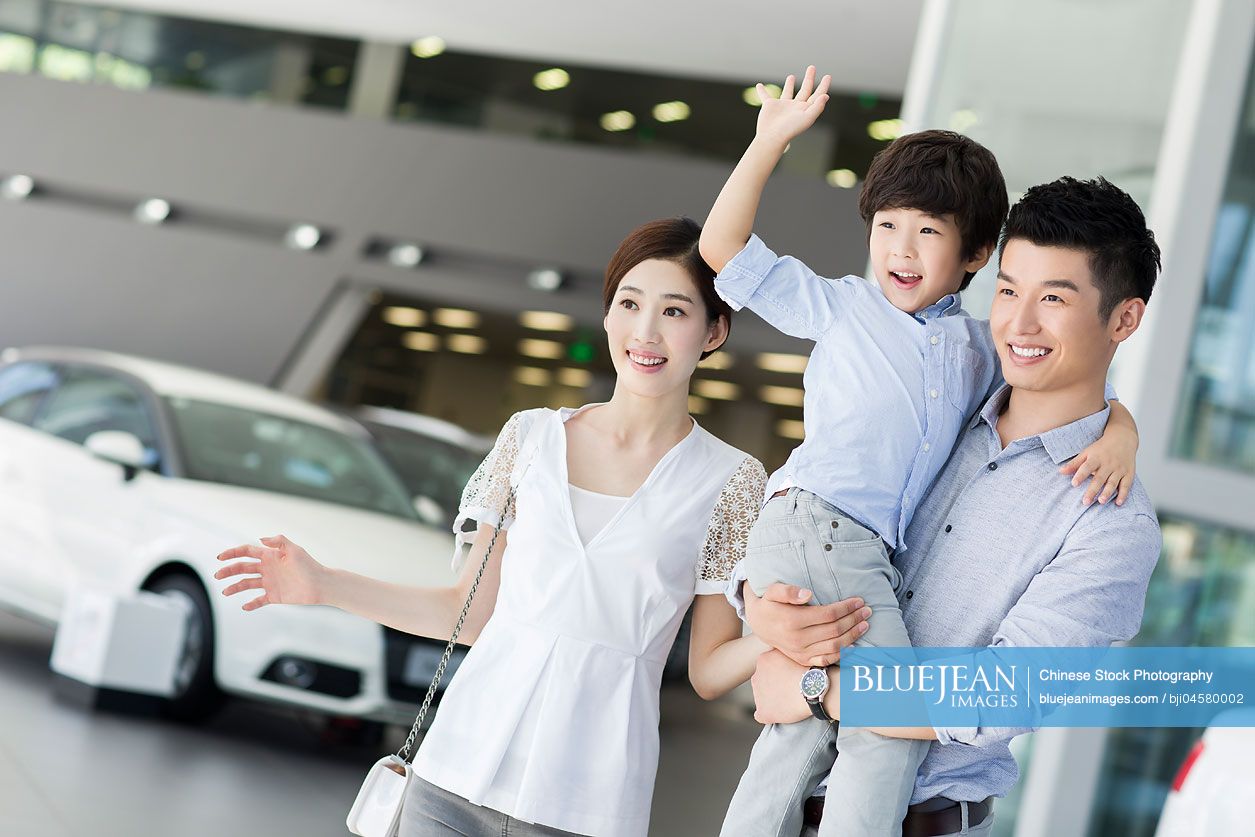 young-chinese-family-looking-at-new-car-in-showroom-high-res-stock