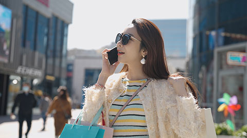 Cheerful young Chinese woman walking with shopping bags,4K