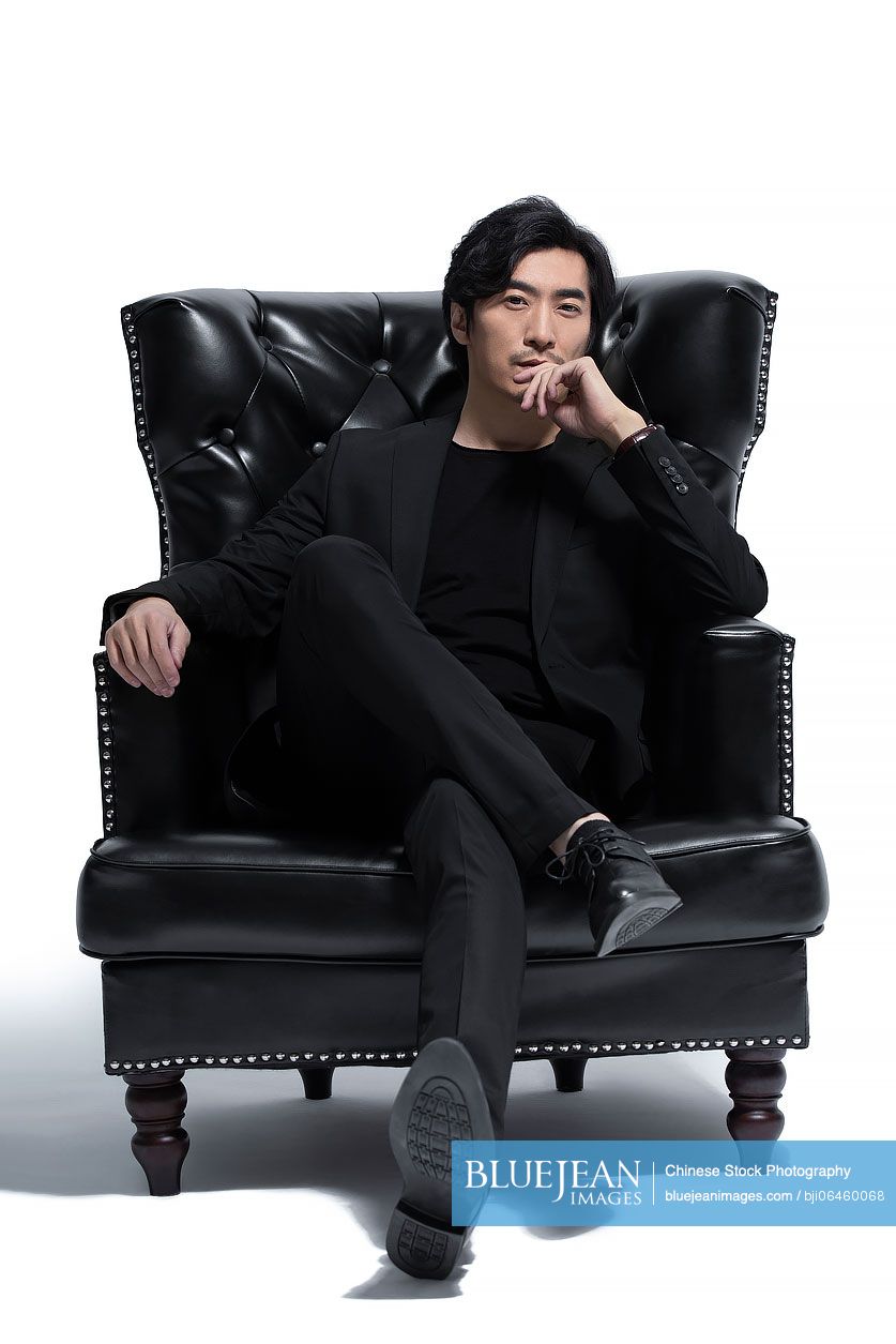Mid adult Chinese man sitting on a luxury sofa