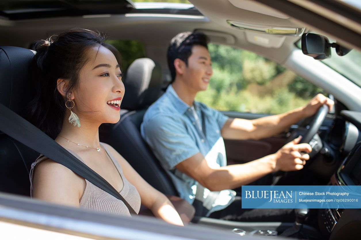 Happy young Chinese couple enjoying road trip