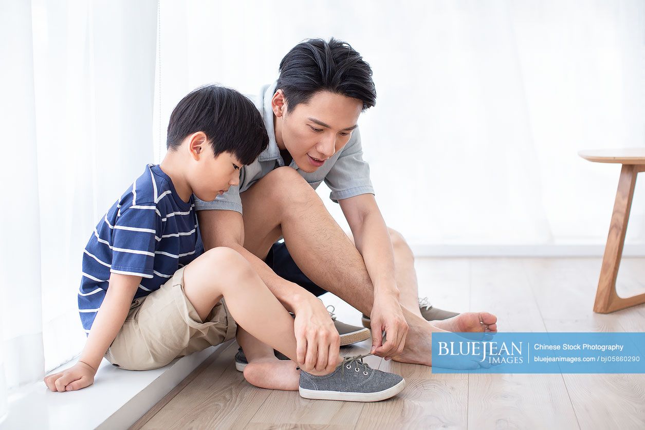 Chinese father teaching his son to tie shoelaces
