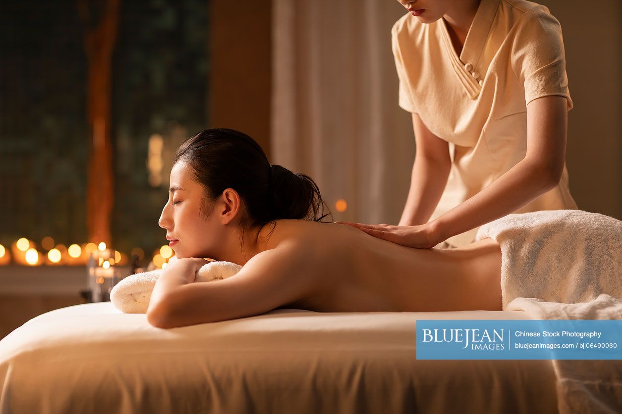 Young Chinese woman receiving back massage at spa center
