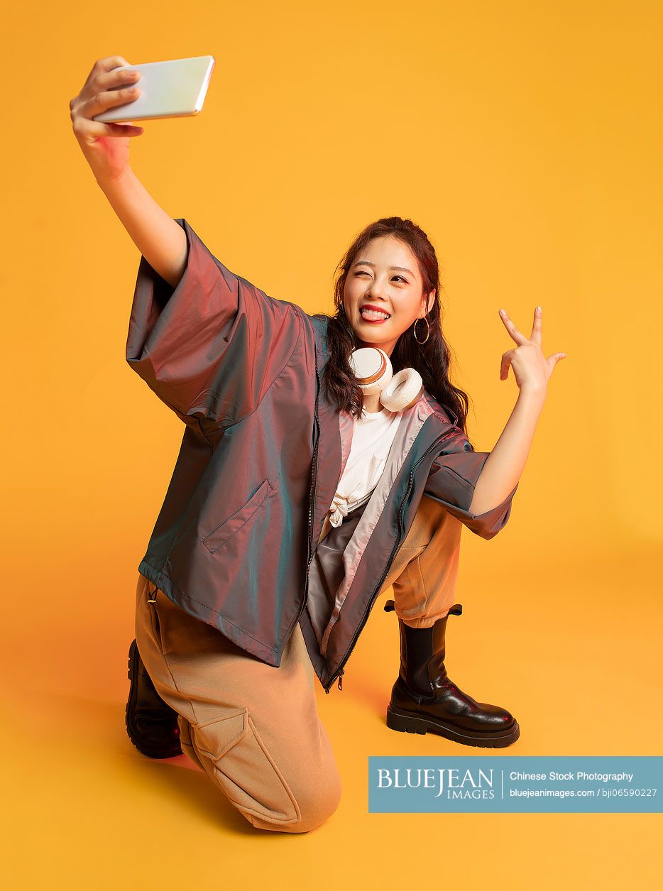 Studio shot of fashionable young Chinese woman holding a smart phone