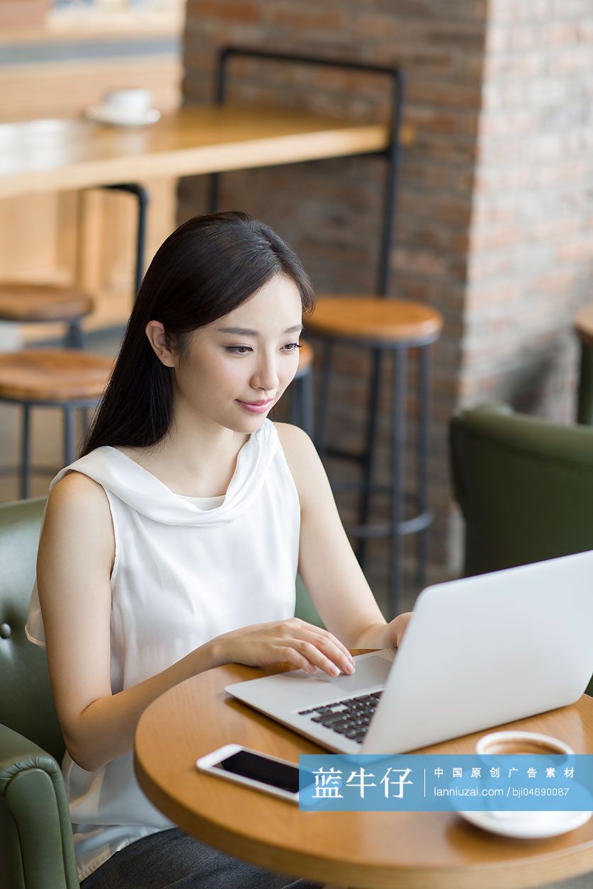 年轻女士在咖啡厅使用笔记本电脑工作