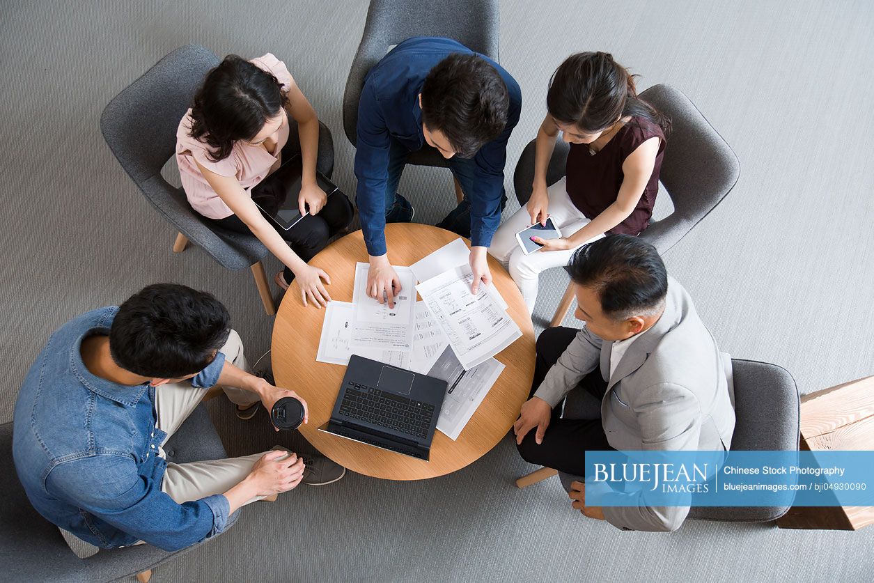 Chinese business people talking in meeting with a laptop