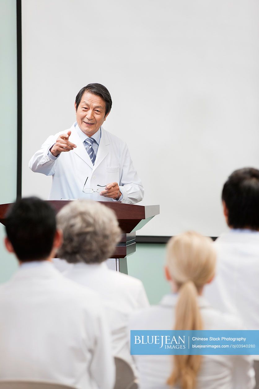 Senior Chinese doctor giving speech in boardroom