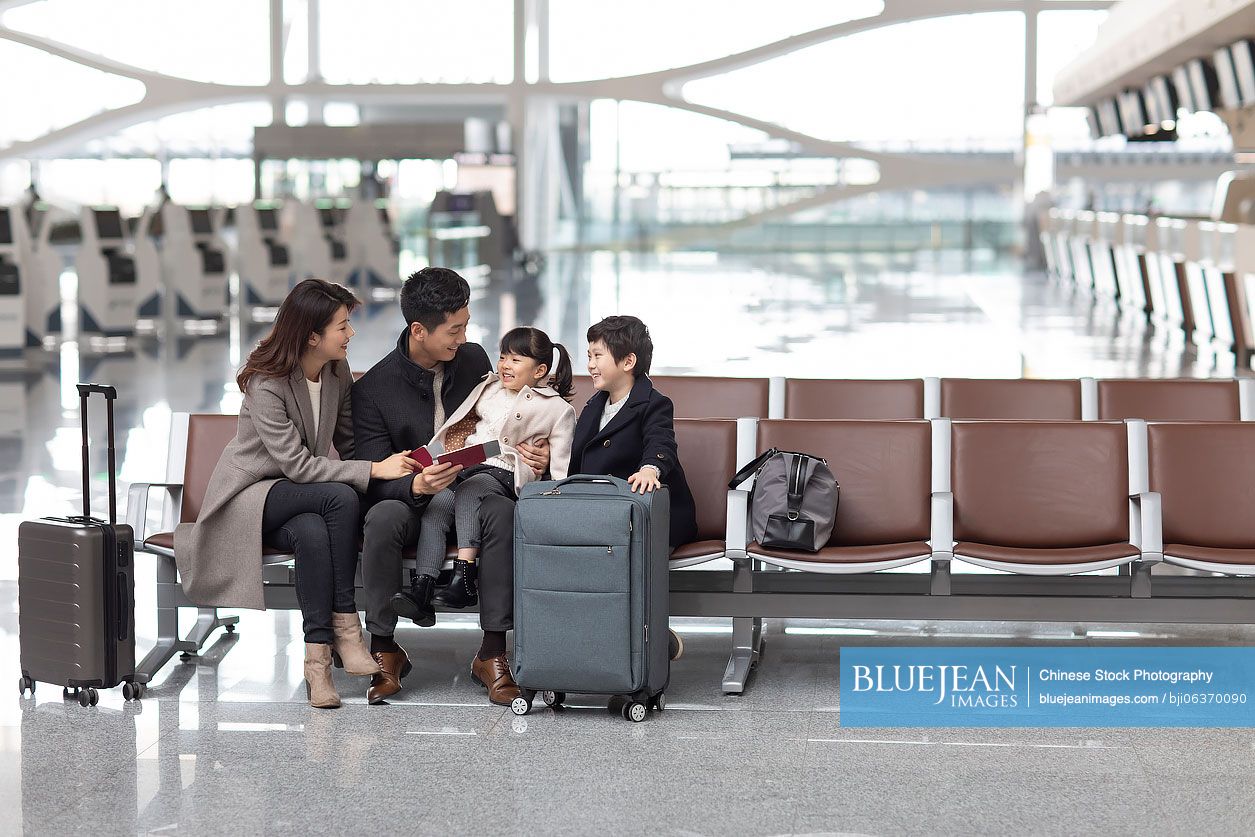 Happy young Chinese family waiting for flight at the airport