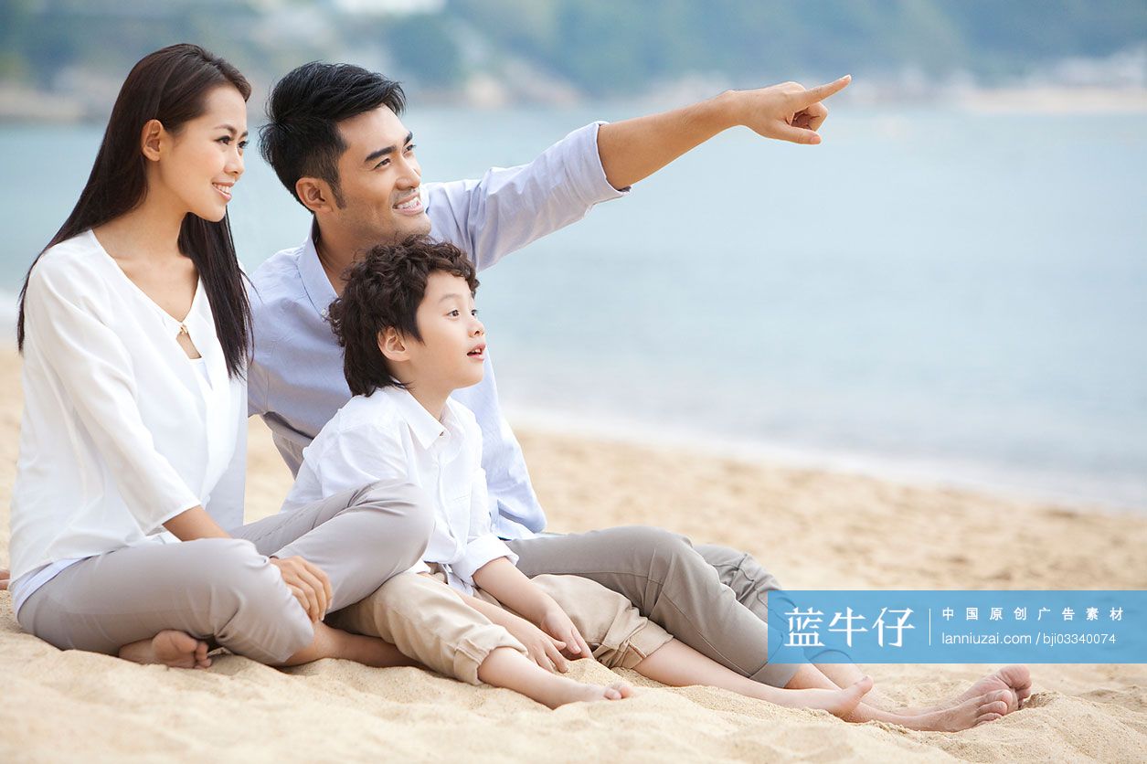 快乐的一家人坐在沙滩上手指前方