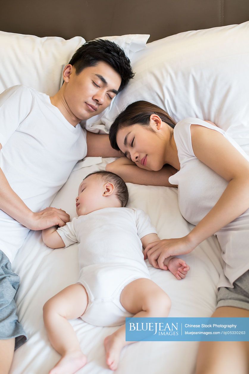 Young Chinese family sleeping in bed