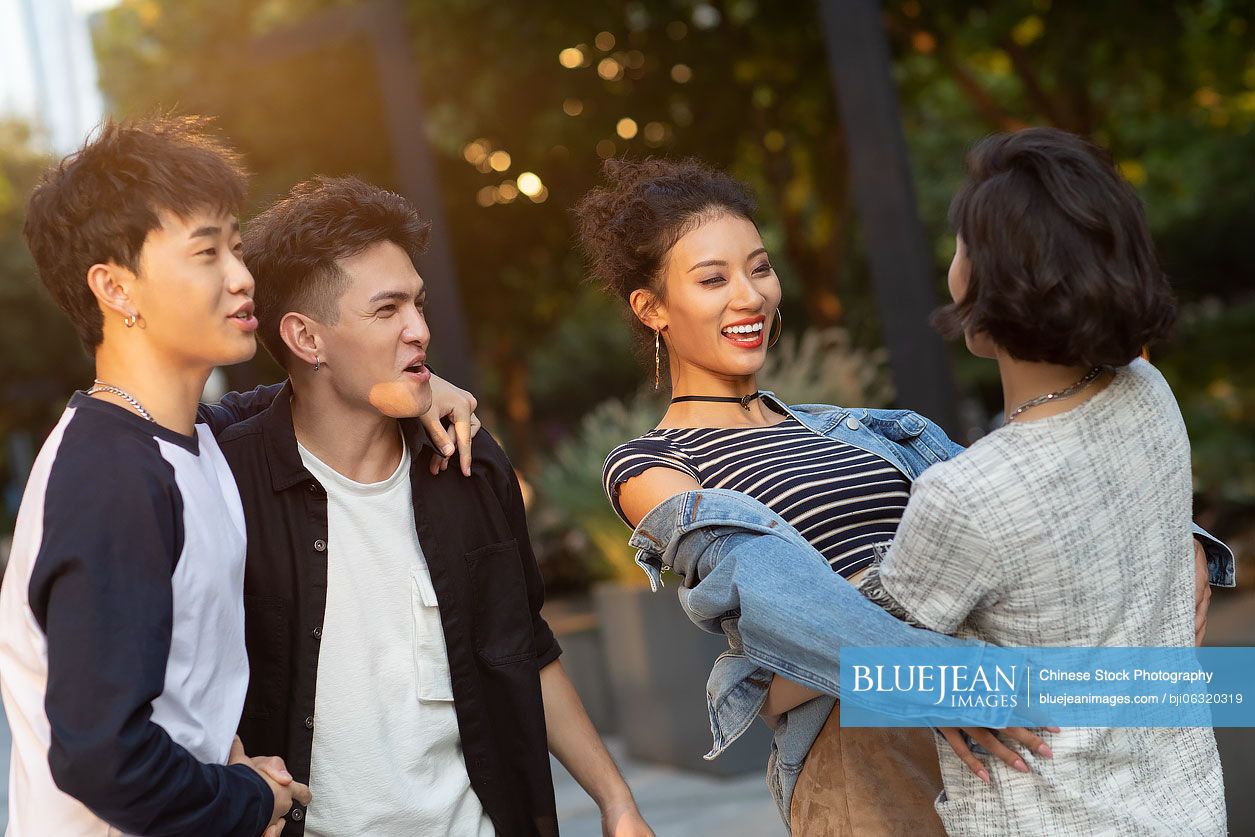 Fashionable young friends greeting and hugging on street