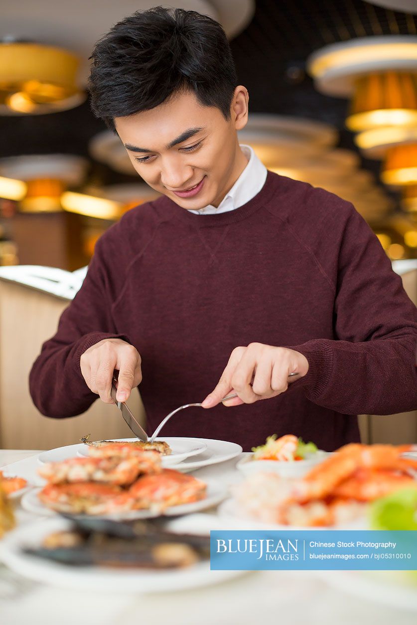 Cheerful young Chinese man having buffet dinner