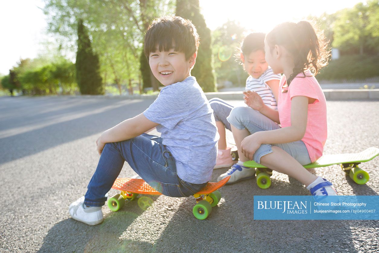 Happy Chinese children sitting on skateboards