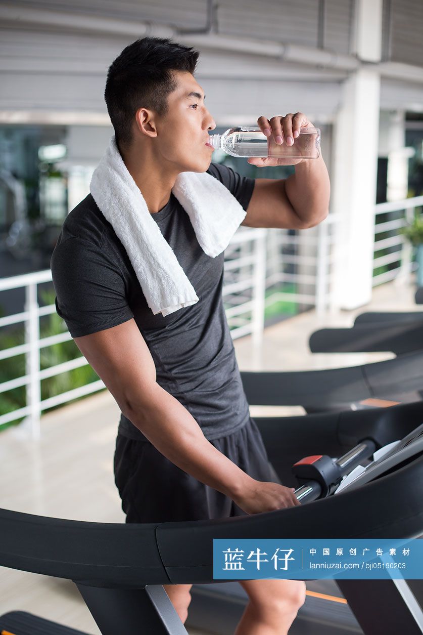 年轻男子在健身房喝水休息