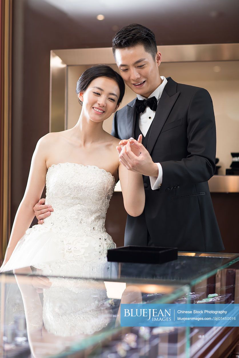 Happy Chinese bride and groom shopping in jewelry store 