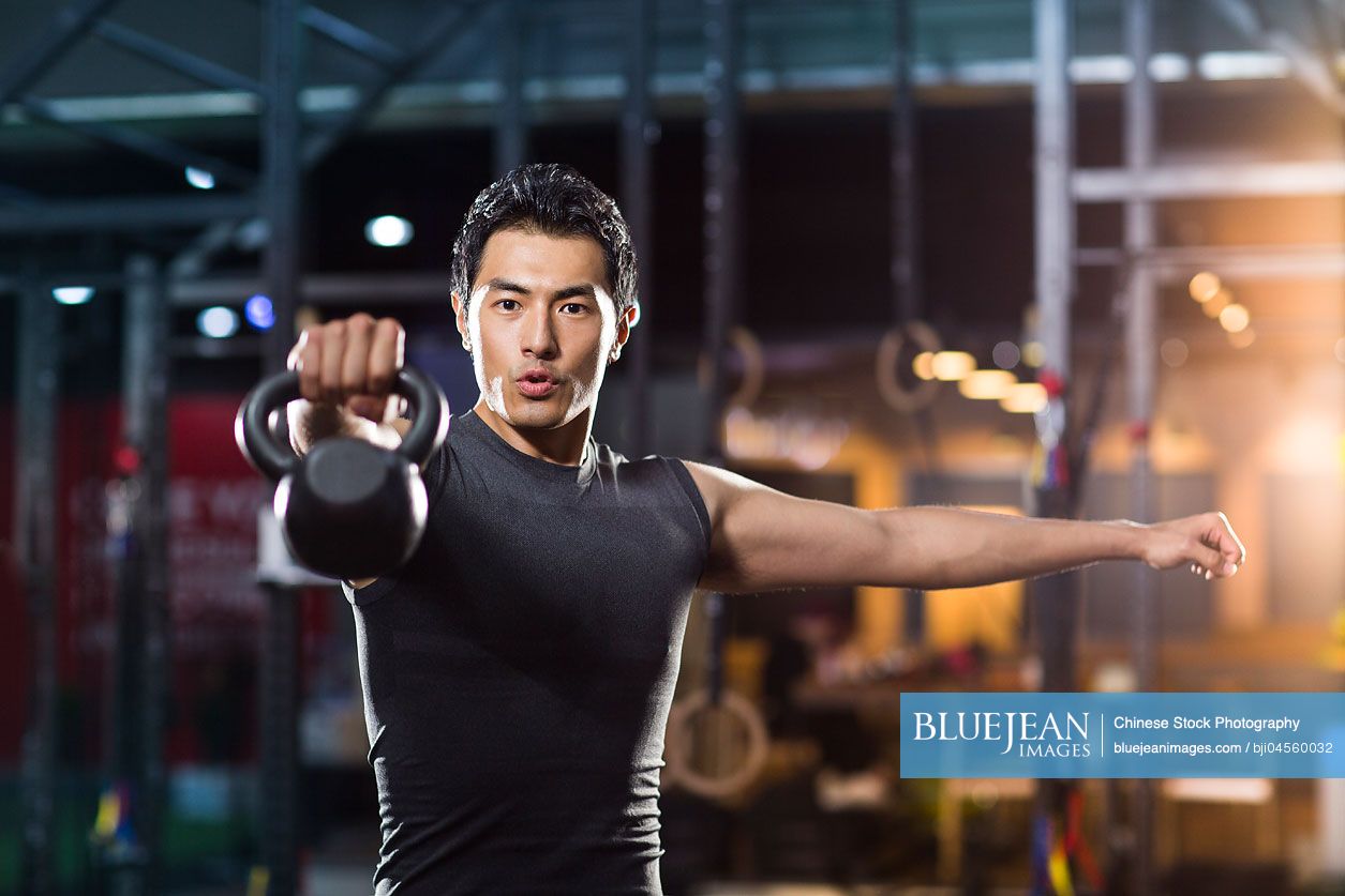 Young Chinese man training with kettlebell in crossfit gym