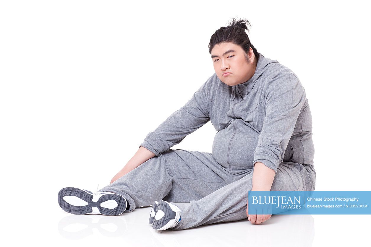 Unhappy Chubby Chinese man sitting on the ground