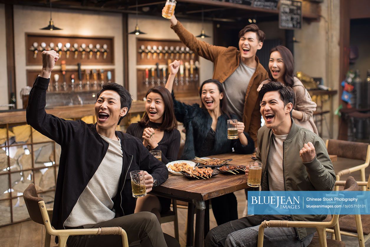 Happy Chinese friends cheering in bar