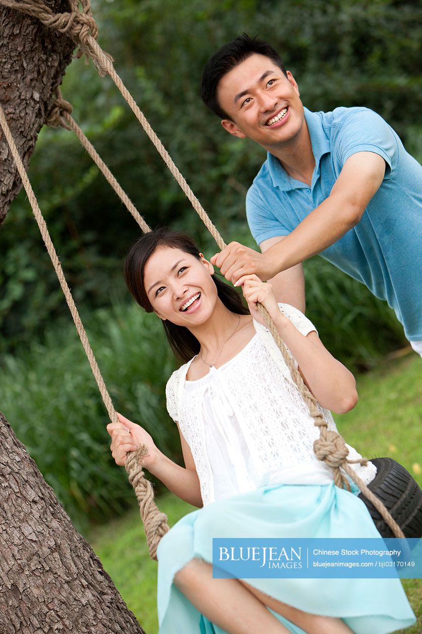 Joyful young Chinese couple playing on a swing-High-res stock photo for ...