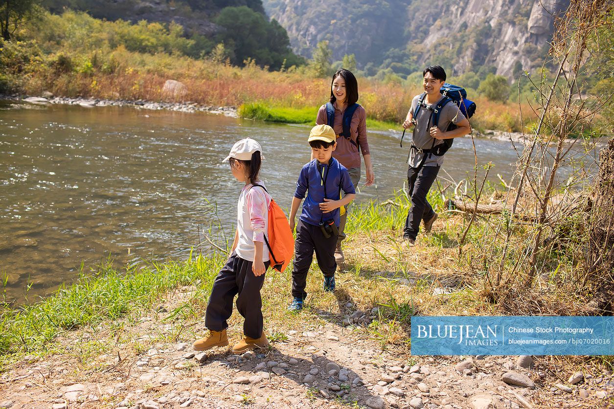 Happy young Chinese family hiking outdoors