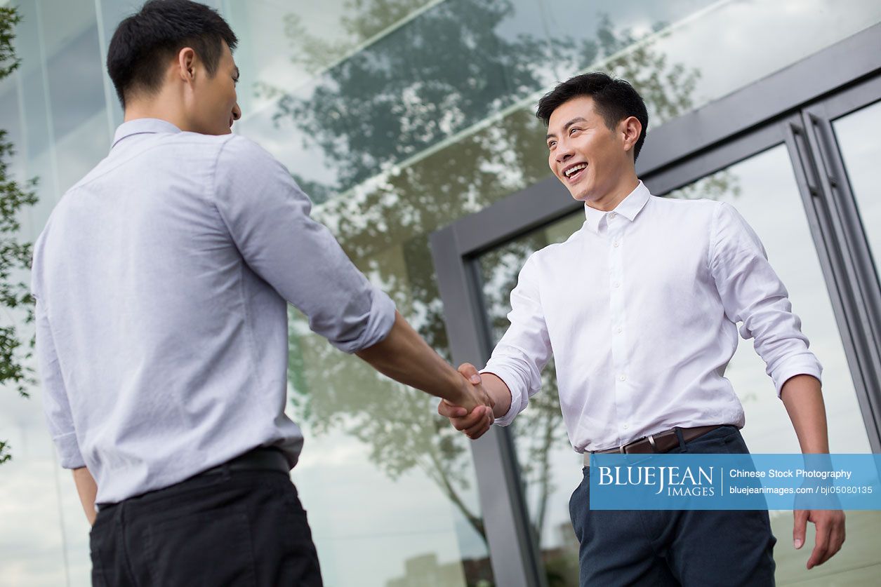 Young Chinese business person shaking hands outdoors