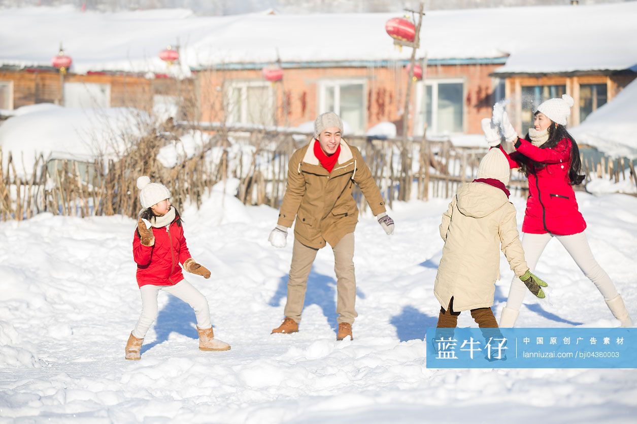 年轻的家庭在雪地上打雪仗