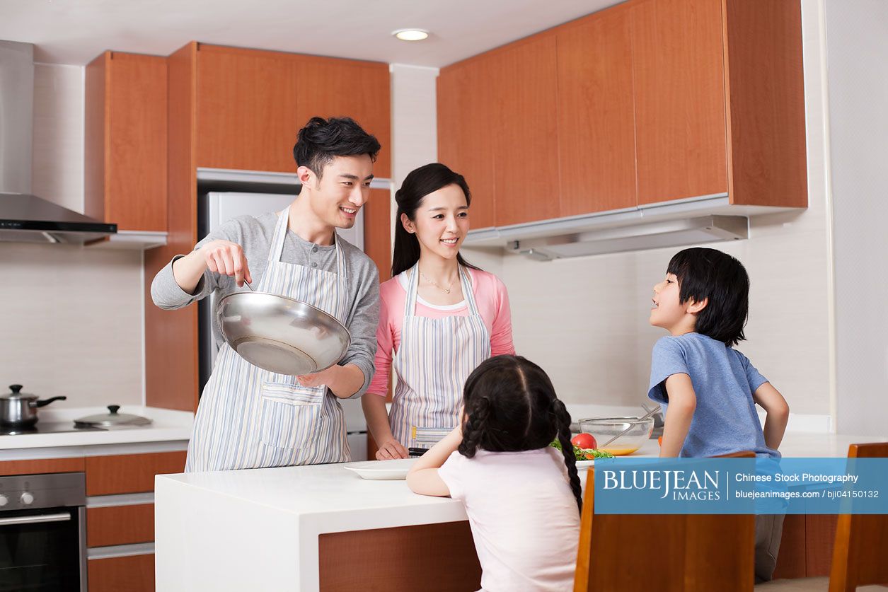 Happy young Chinese family cooking in kitchen