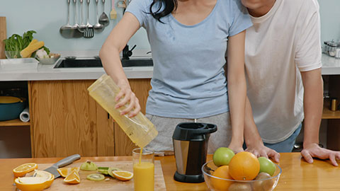 Happy young Chinese couple drinking juice in kitchen,4K