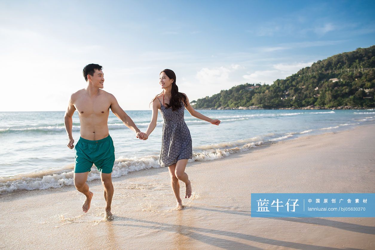 快乐的年轻情侣在沙滩奔跑