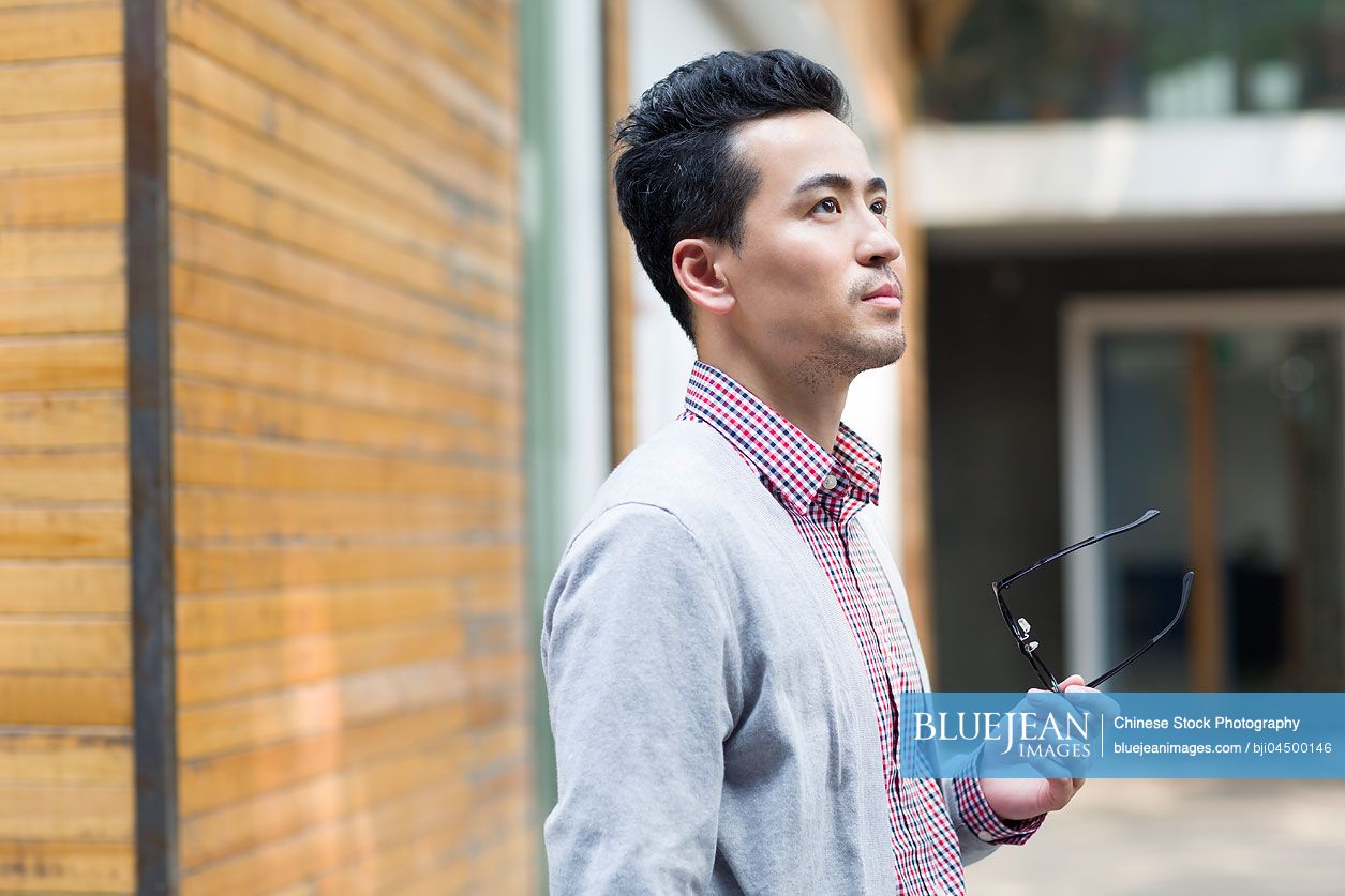 Chinese man holding a pair of glasses