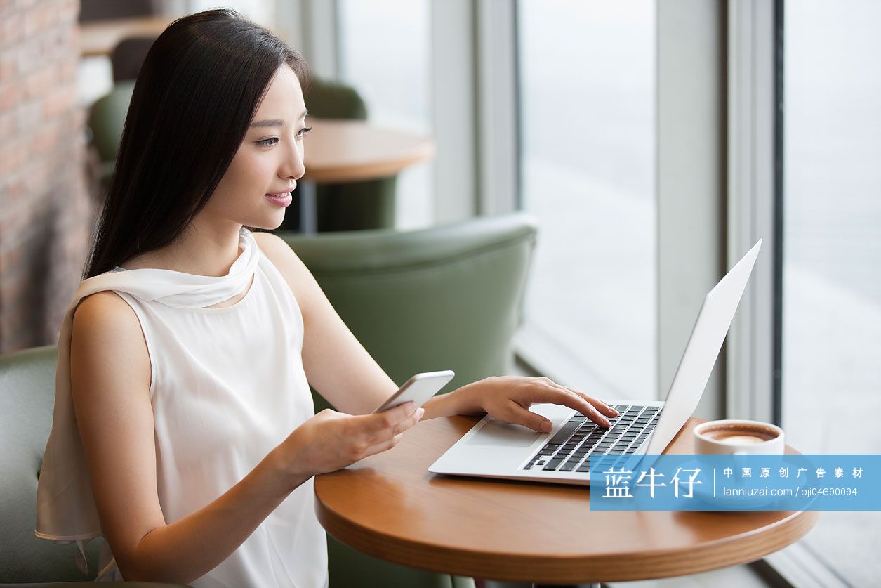 年轻女士在咖啡厅使用笔记本电脑工作