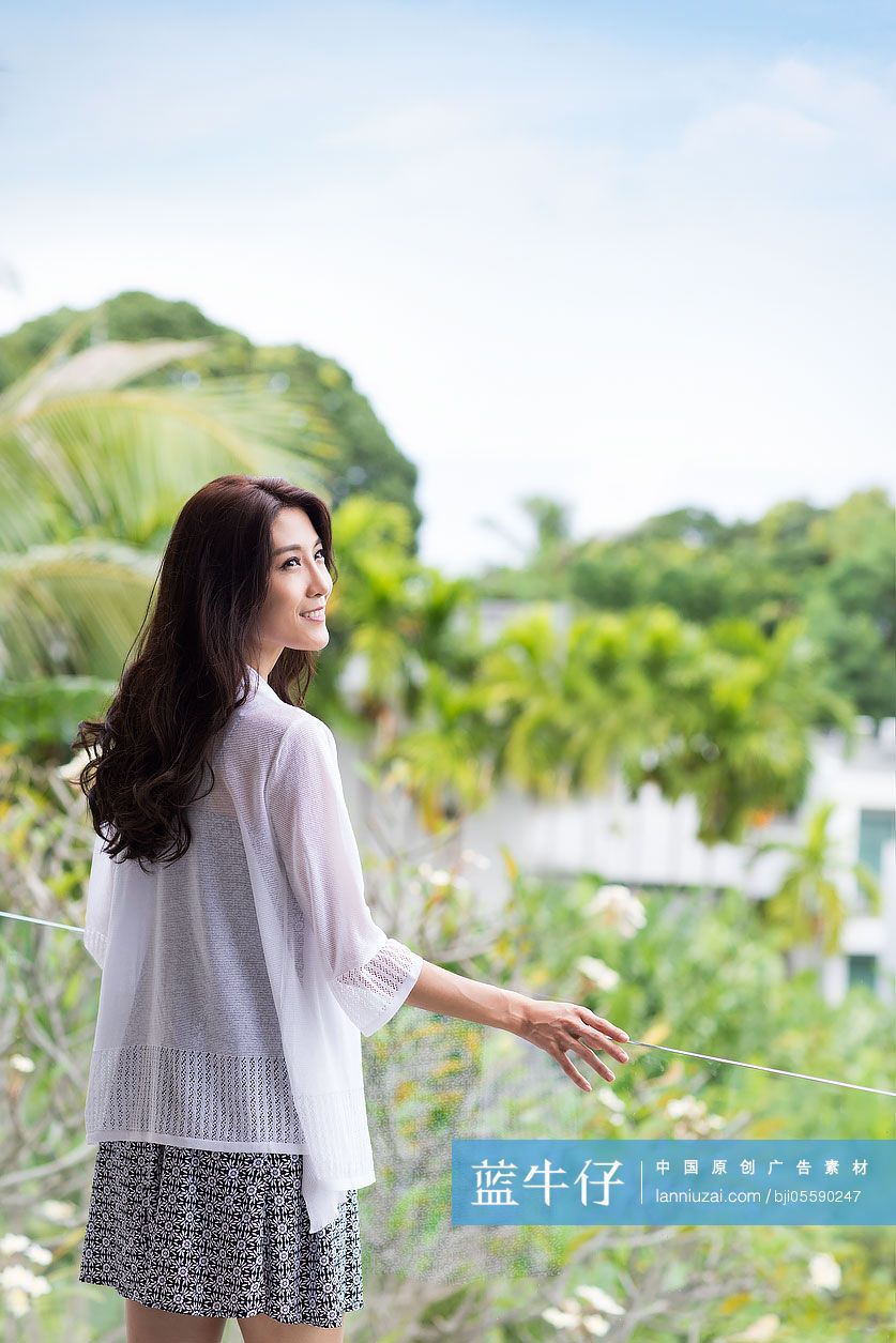 快乐的年轻女子在阳台上看风景