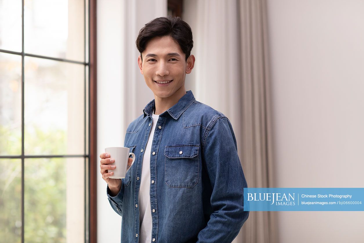 Happy young Chinese man holding coffee