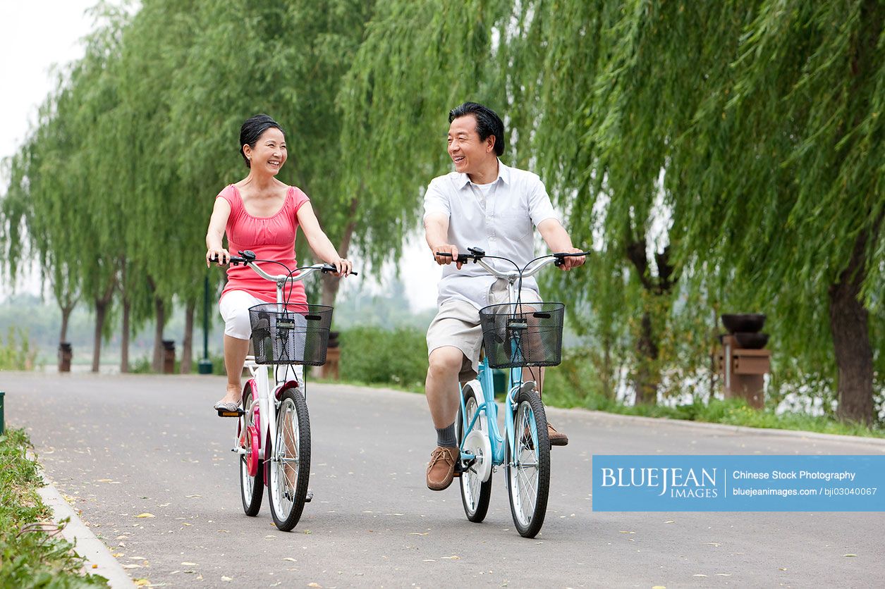 Senior Chinese couple cycling in park