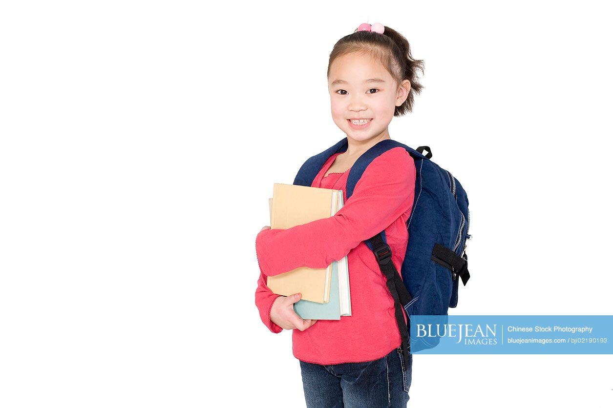 A young Chinese girl holding her school books