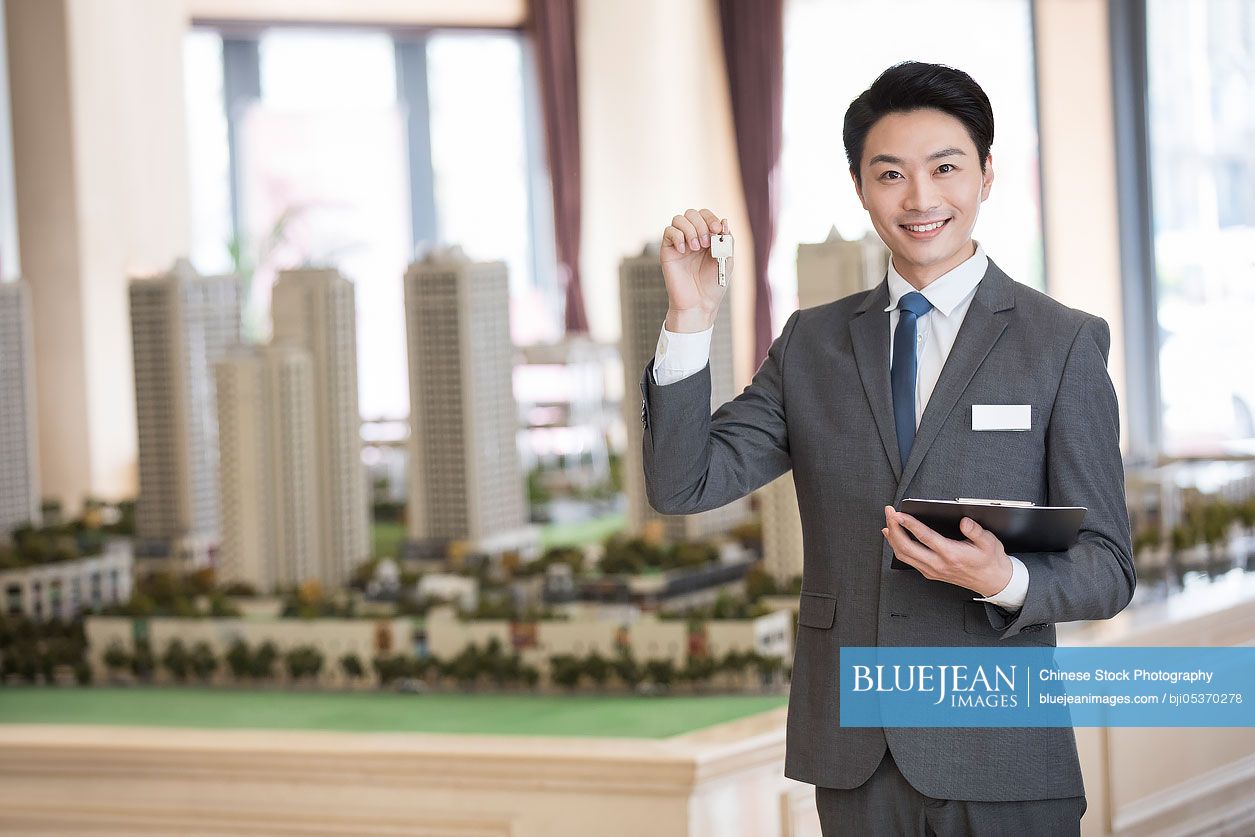 Confident Chinese realtor holding house keys