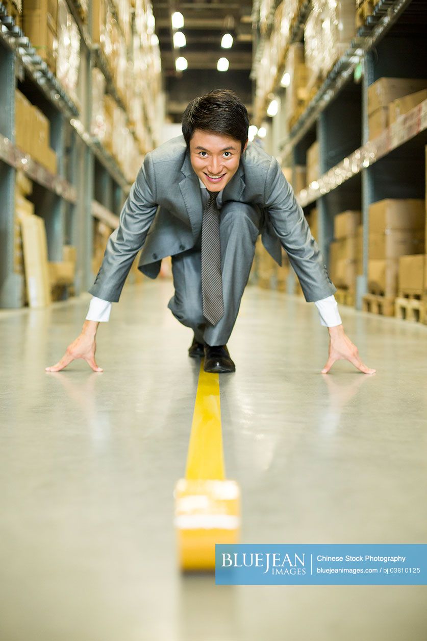 Confident Chinese businessman ready to run in warehouse